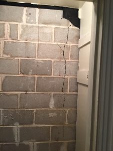 Cinder block basement wall exhibiting cracks due to foundation settling